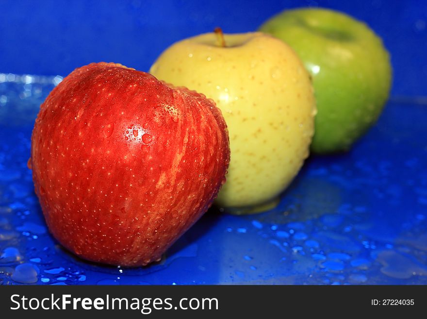 Red, yellow and green wet apple on a blue background. Red, yellow and green wet apple on a blue background