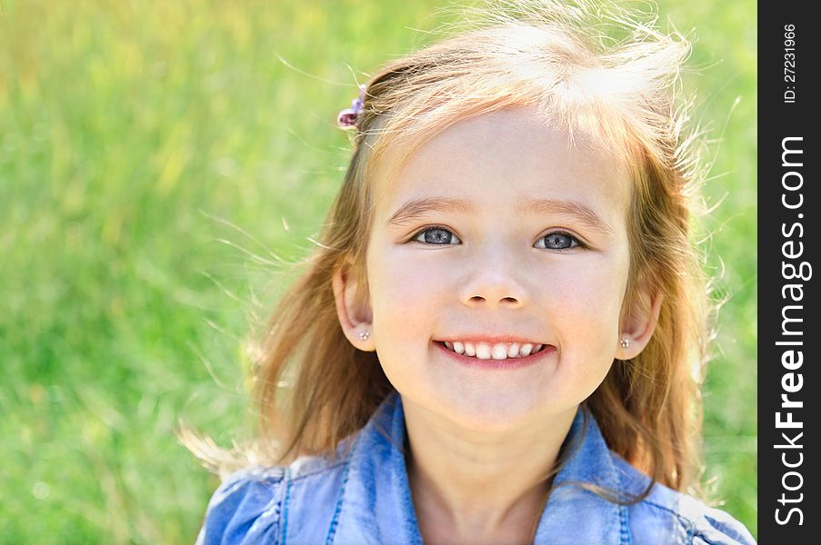 Outdoor portrait of smiling little girl on the meadow