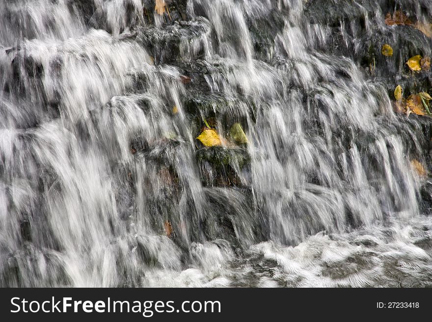 Yellow leaf on a rock in the middle of the waterfall. Yellow leaf on a rock in the middle of the waterfall