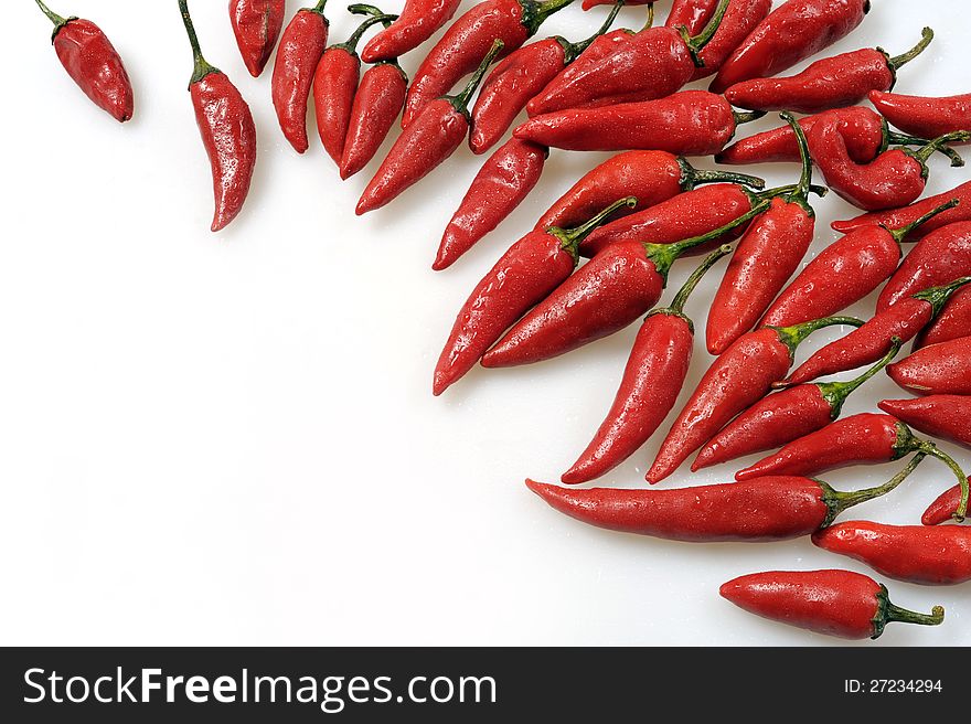 Red hot pepper is heaped on a white background. Consumed. Red hot pepper is heaped on a white background. Consumed.