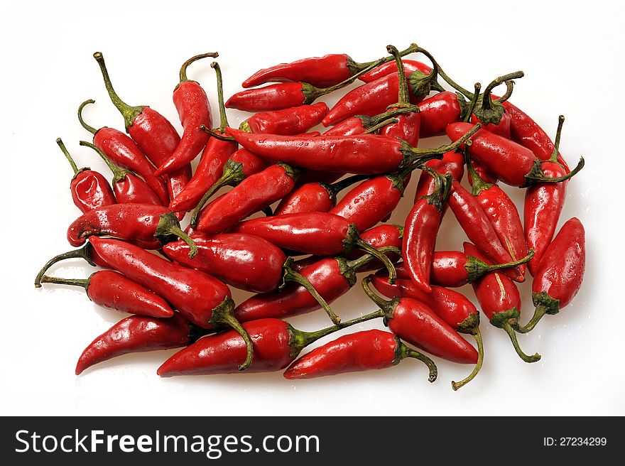 Red hot pepper is heaped on a white background. Consumed. Red hot pepper is heaped on a white background. Consumed.