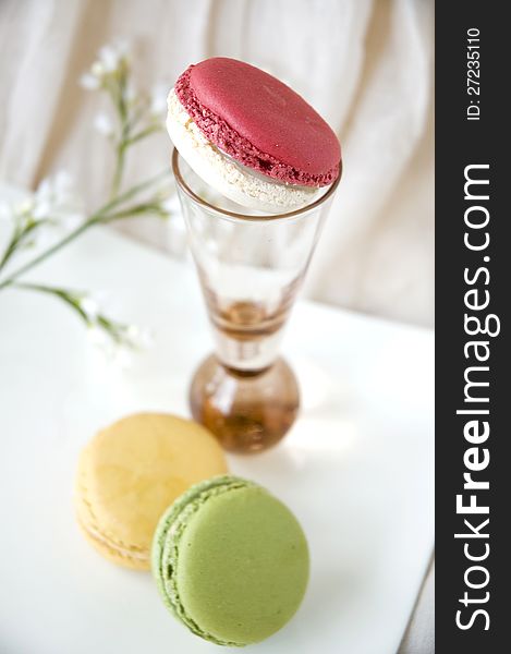 Macarons on plate with pink macaron on pink glass. Macarons on plate with pink macaron on pink glass