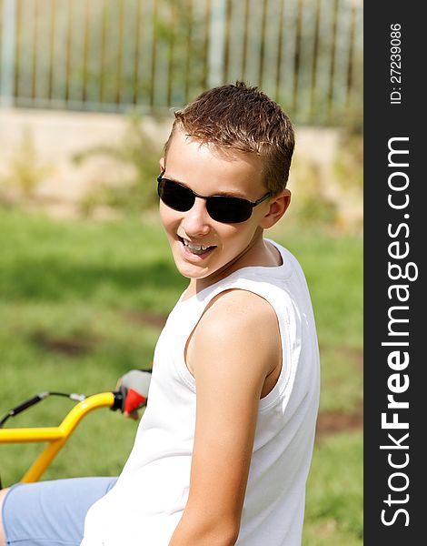 Boy in glasses on a bike outside in the summer