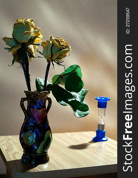 Vase with yellow roses and hourglass