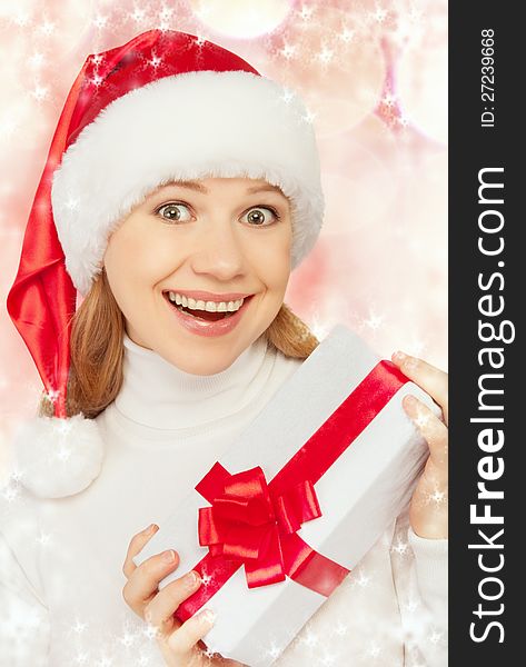 Young cheerful woman in a Christmas hat with a gift with a red ribbon