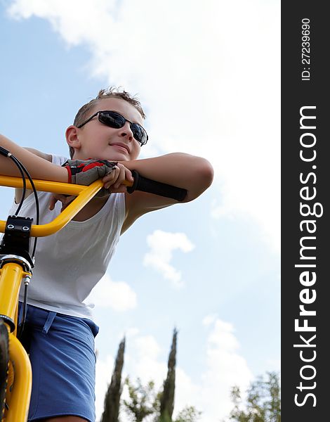 Pretty boy on a bike outside in the summer day