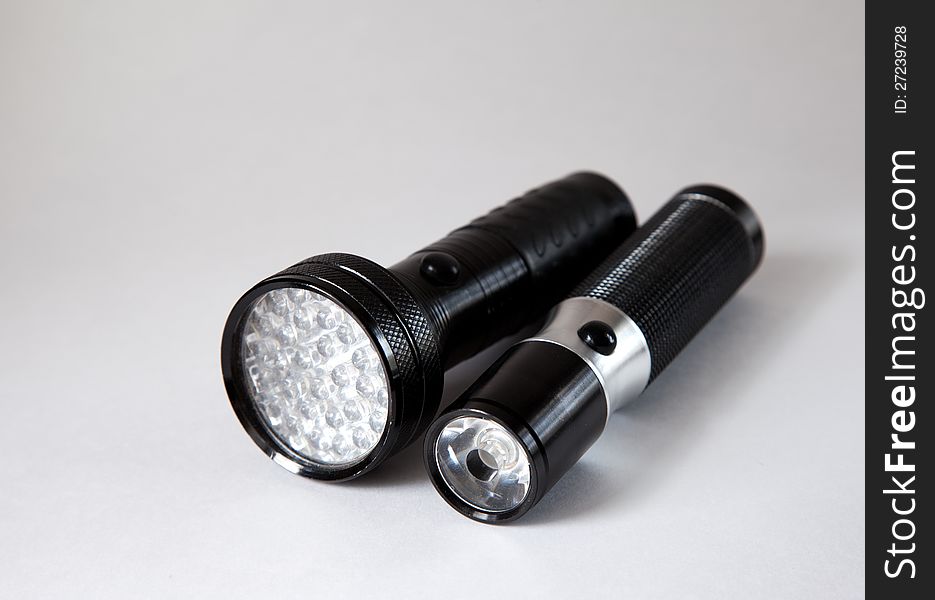 Two black metal flashlights on the light background