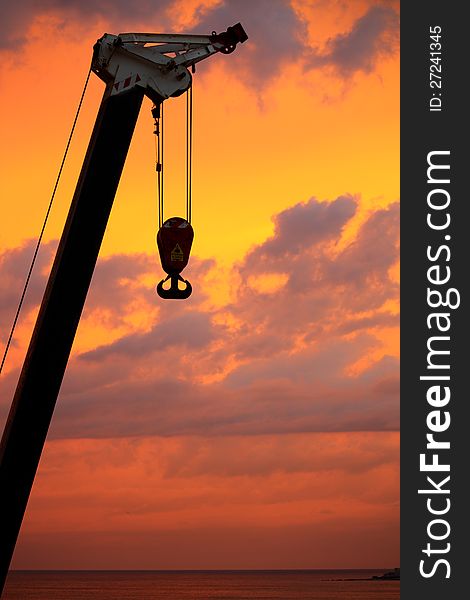 At dawn a boom lift hook stands on a natural background, it starts working. At dawn a boom lift hook stands on a natural background, it starts working.