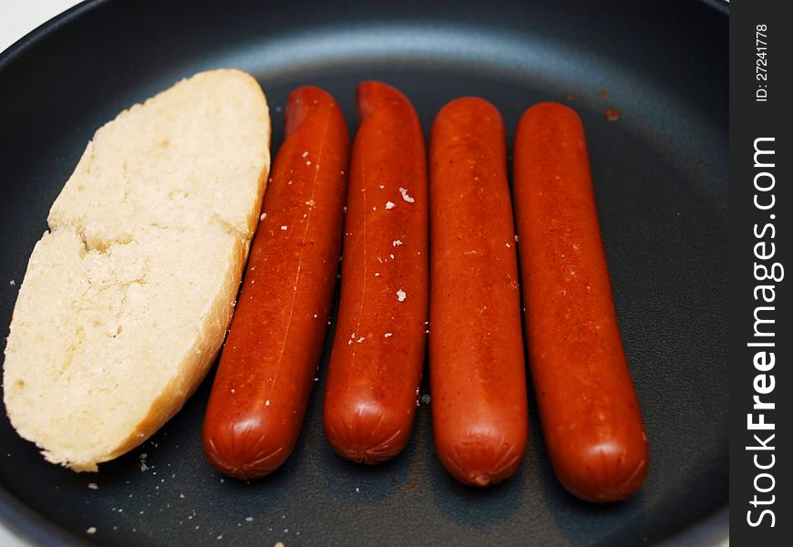 Frying sausages in a non-stick frying pan, with white bread