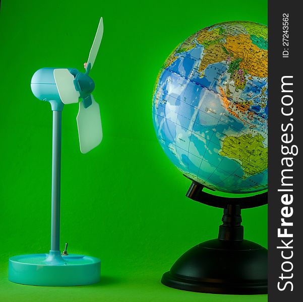 Wind turbine model and globe on green background. Wind turbine model and globe on green background