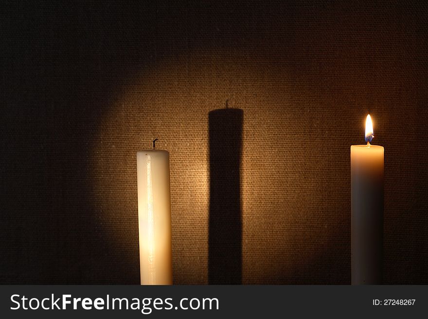 Extinguished and lighting candles with long shadow against canvas background. Extinguished and lighting candles with long shadow against canvas background