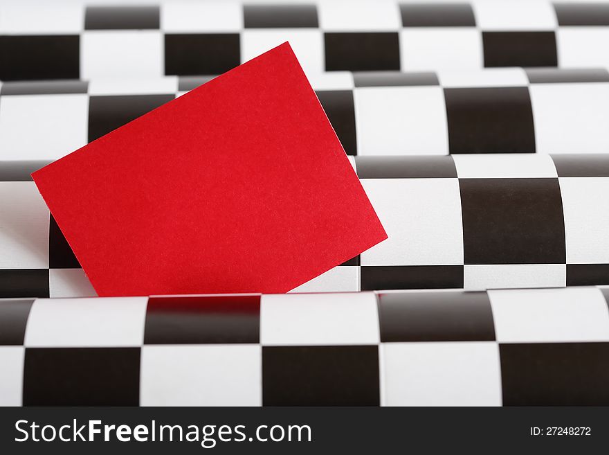 Blank red paper for text on black and white checkered background. Blank red paper for text on black and white checkered background