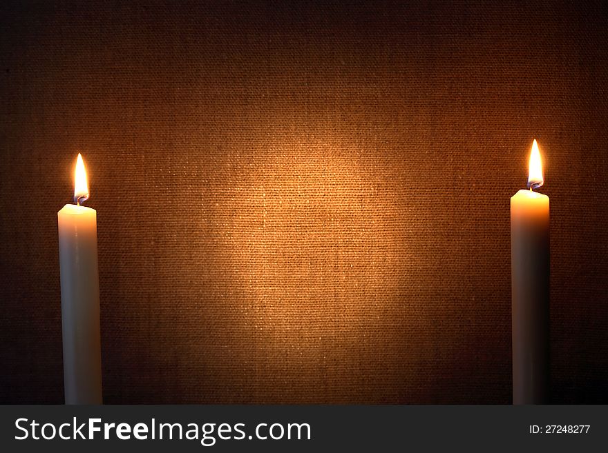 Pair of lighting candles against canvas background. Pair of lighting candles against canvas background