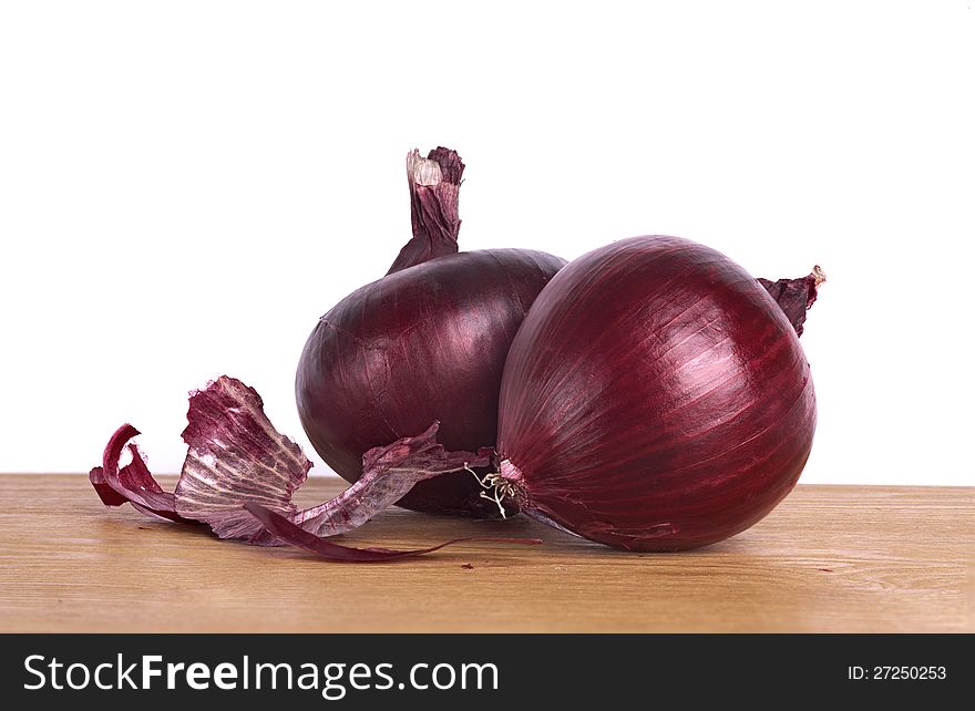 Red onions on wooden board.