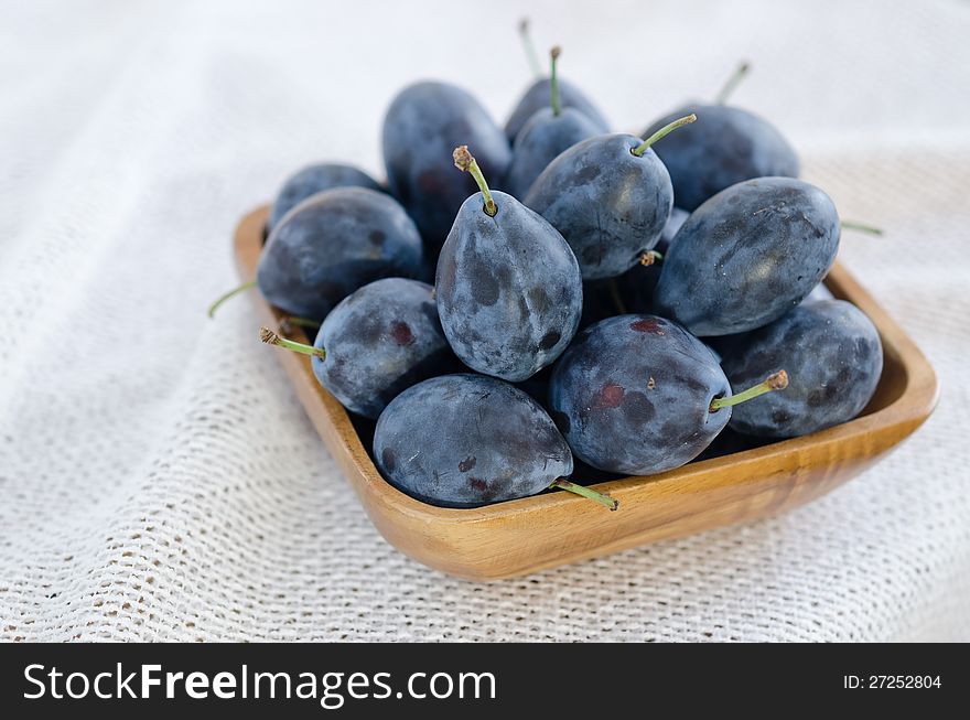 Fresh plums in a wooden bowl on a white background. Fresh plums in a wooden bowl on a white background