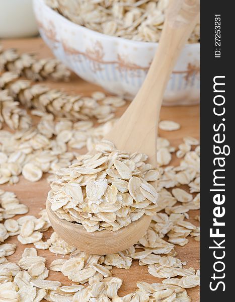 Oat flakes in wooden spoon, scattered on a table. Oat flakes in wooden spoon, scattered on a table