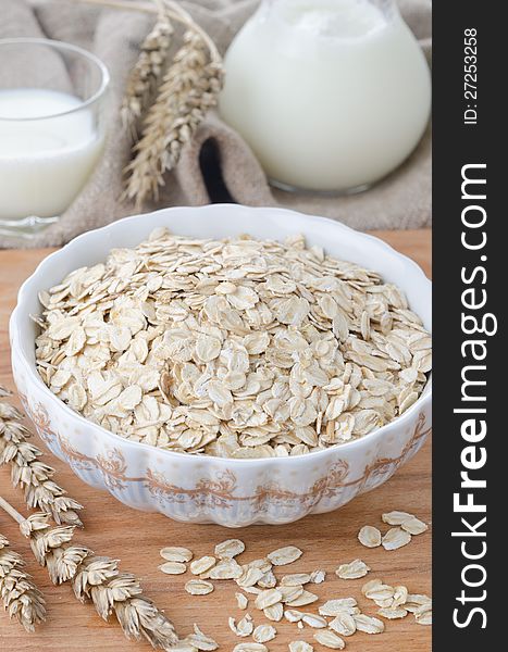 Rolled oats in a ceramic bowl on wooden table. Rolled oats in a ceramic bowl on wooden table