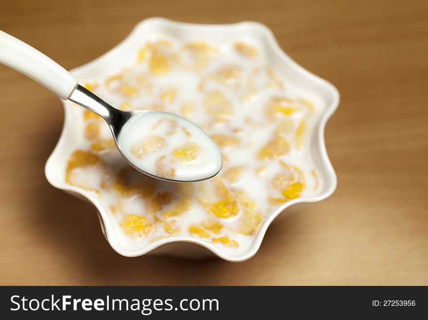 Yellow cornflakes in white bowl with milk. Yellow cornflakes in white bowl with milk