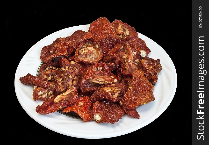 Dry tomatoes on white plate isolated over black background. Dry tomatoes on white plate isolated over black background