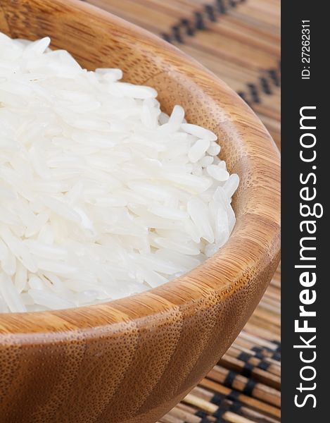 Perfect White Rice in Wooden Bowl closeup on Straw mat background