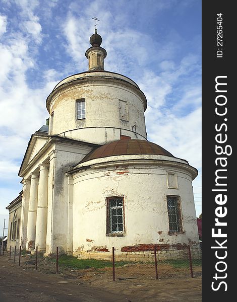 Photo of ancient Russian white church with a dome and columns against blue sky with clouds. Photo of ancient Russian white church with a dome and columns against blue sky with clouds