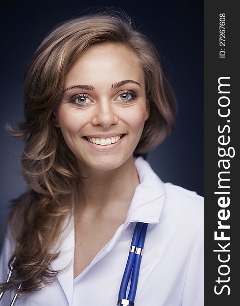 Young doctor woman with stethoscope on dark blue background