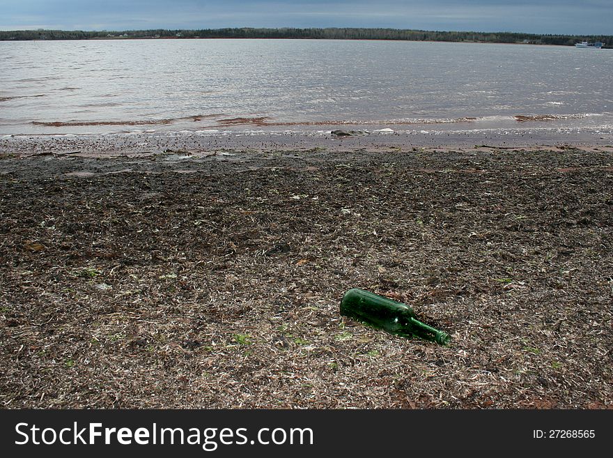 Green wine bottle pollutes a beach in Prince Edward Island