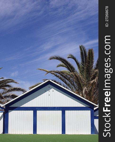 Bathing hut with palmas trees over blue sky