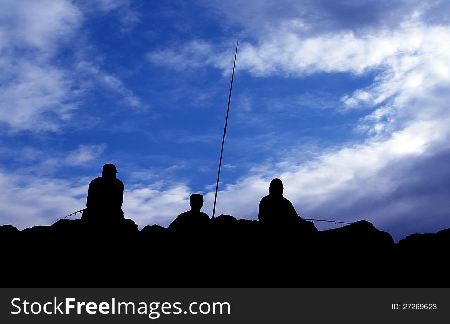 Three men fishing over reef with blue sky background. Three men fishing over reef with blue sky background