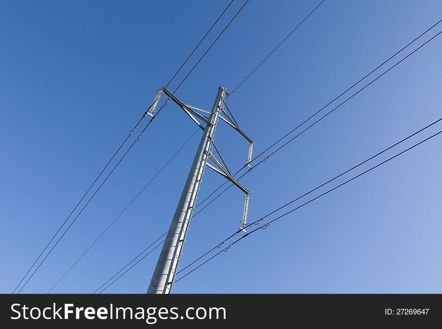 Powerline cables and tower seen from below against blue sky