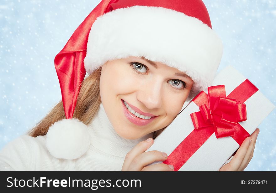 Young beautiful woman in a Christmas hat with a gift with a red ribbon. Young beautiful woman in a Christmas hat with a gift with a red ribbon