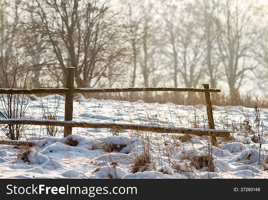 Winter fence with snow and grass around
