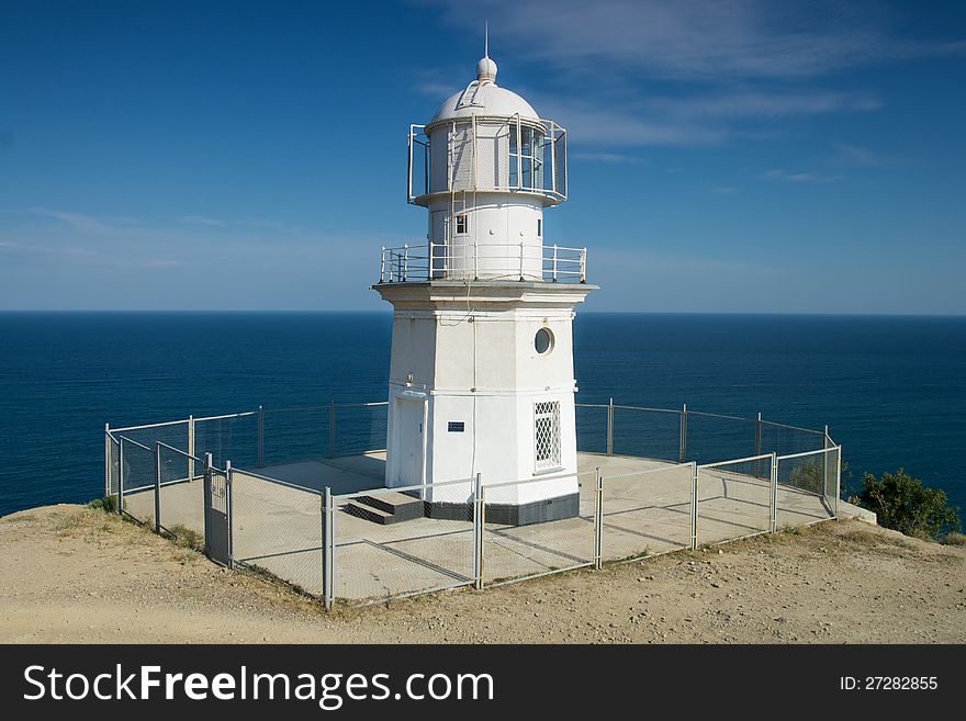 Lighthouse by the sea on a background of blue sky