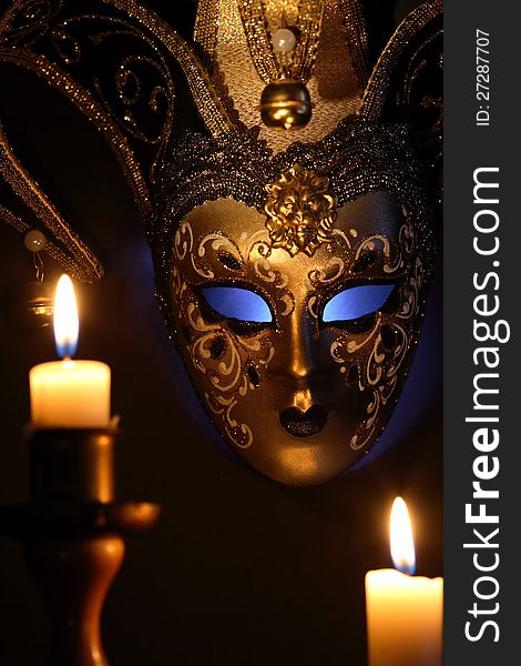 Lighting candles against beautiful classical venetian mask on dark background