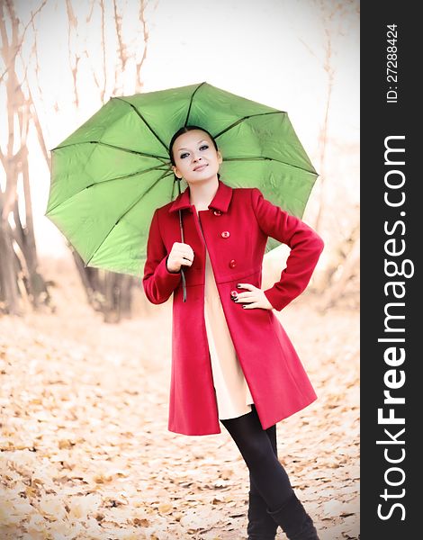 Pretty girl in red coat with umbrella in autumn