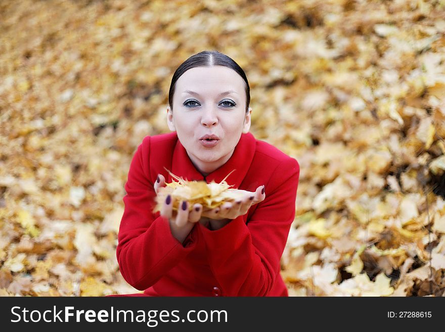 Cute girl in red coat with leaves in autumn