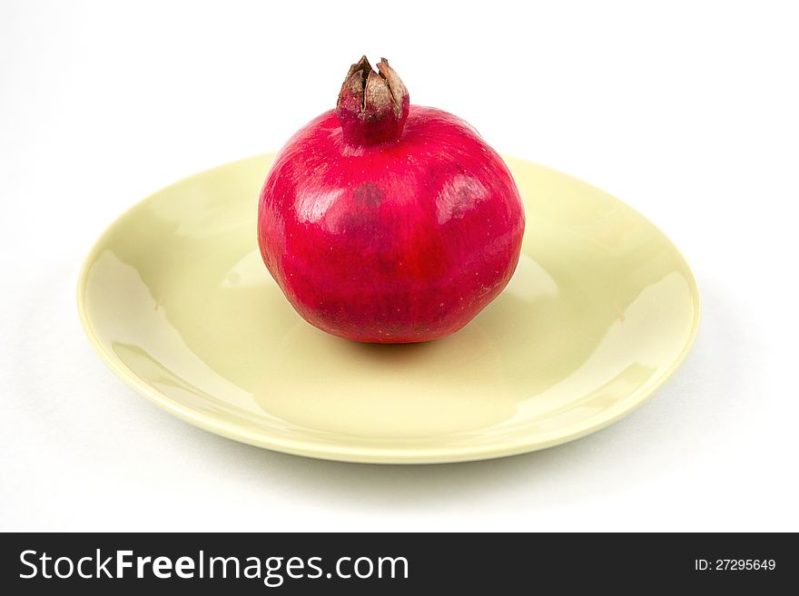 Ripe whole pomegranate on the plate on white background