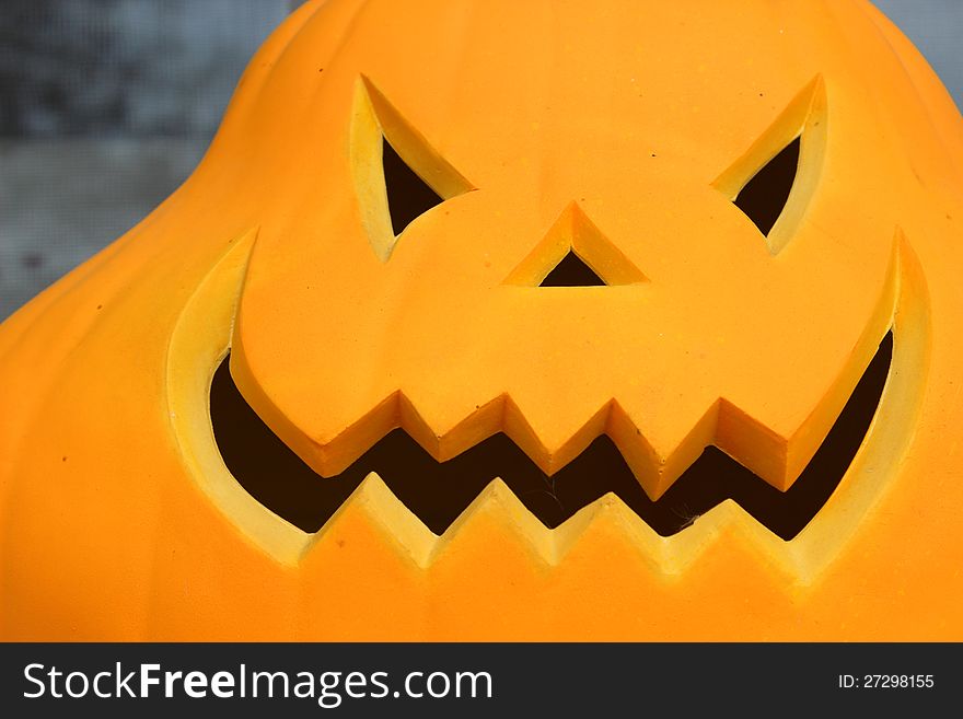 Bright orange face of scary jack-o-lantern face with cut-outs of eyes and grinning mouth . Bright orange face of scary jack-o-lantern face with cut-outs of eyes and grinning mouth .