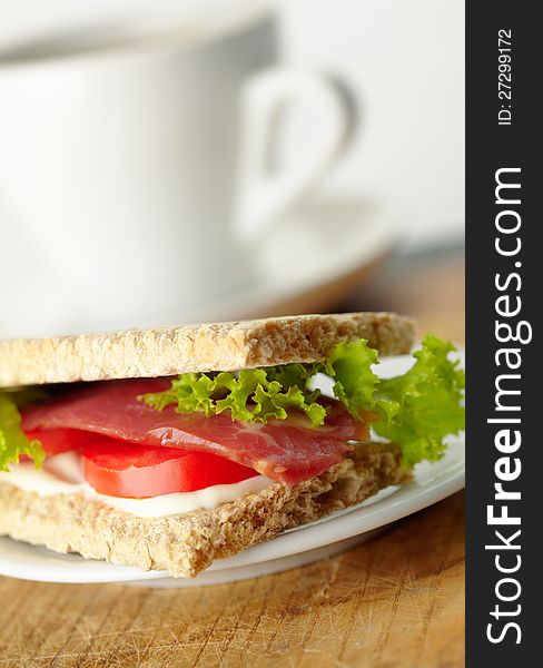 Homemade sandwich with bacon, tomato, rukola and mayonnaise on whole-grain bread