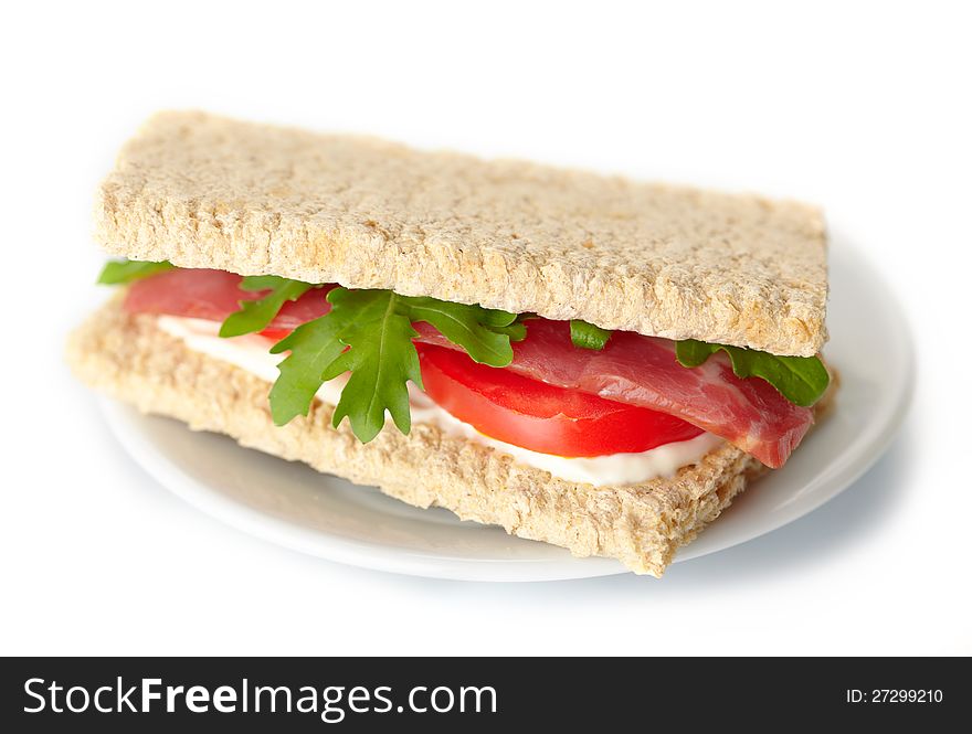 Homemade sandwich with bacon, tomato and rukola on white background