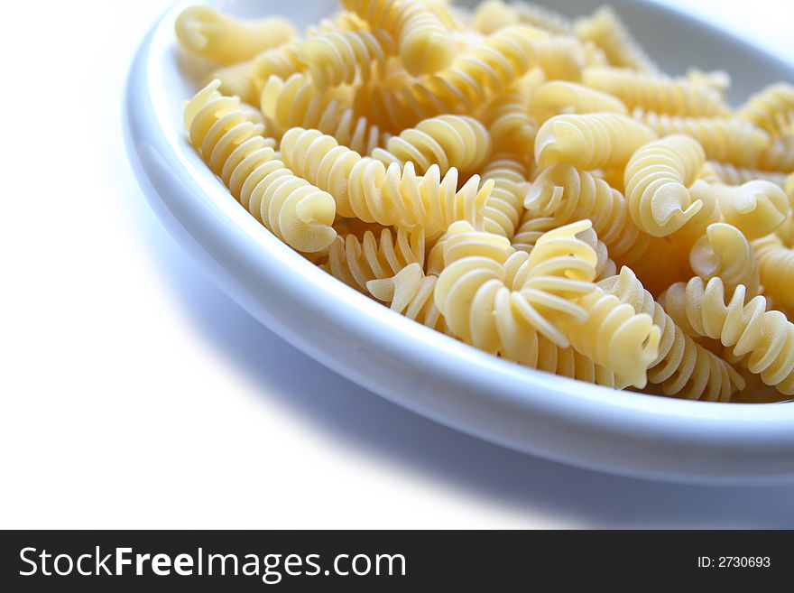 Dish of italian pasta fusilli isolated on white background on the right. Dish of italian pasta fusilli isolated on white background on the right