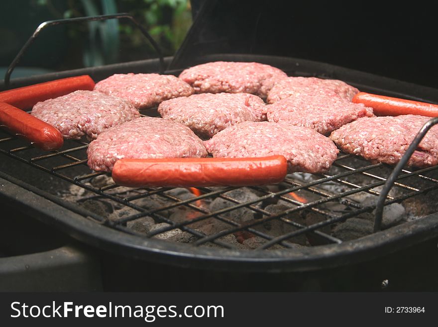 Hamburgers and hotdogs being grilled on outside deck. Hamburgers and hotdogs being grilled on outside deck