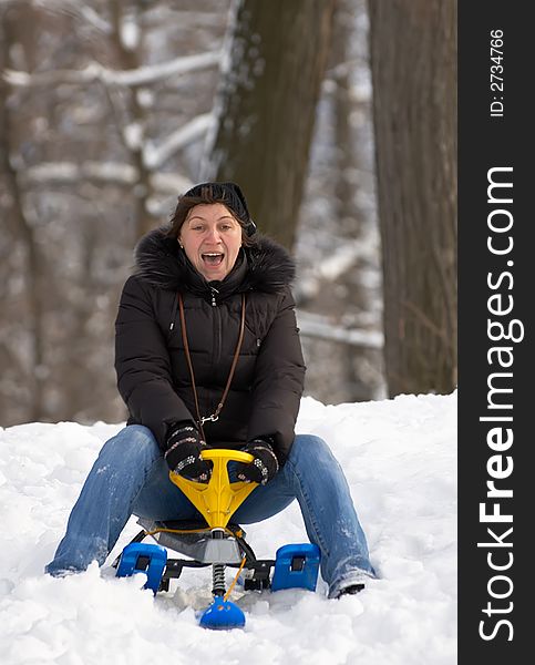 Excited woman, sliding downhill on a sledge.