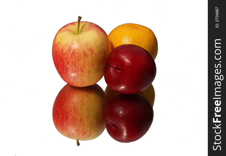 An apple, orange and plum photographed on a mirror. Isolated on white. An apple, orange and plum photographed on a mirror. Isolated on white