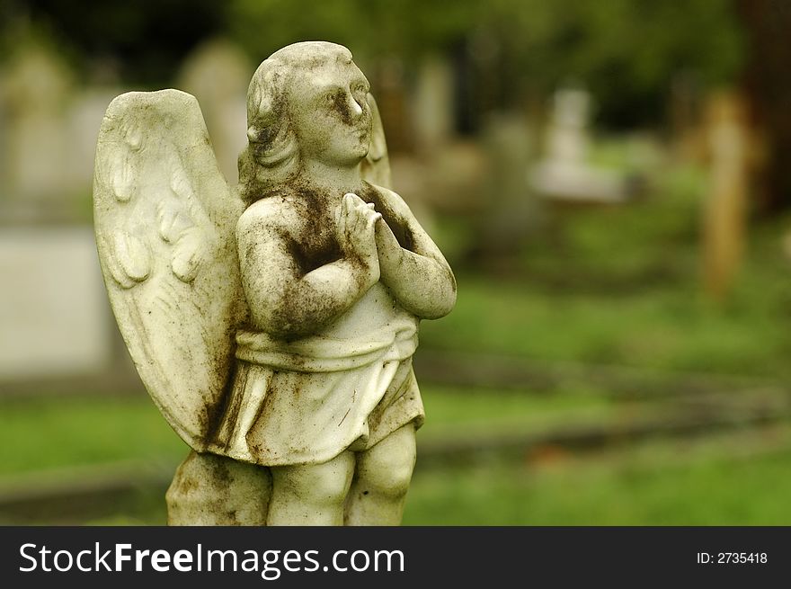 A very old little angel statue at cemetery