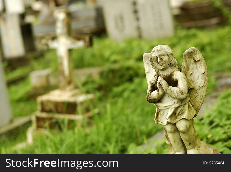 A very old little angel statue at cemetery