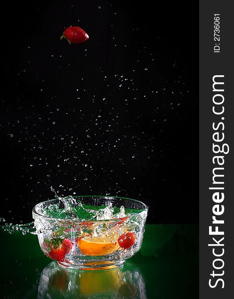 The fruits splash into glass of water. The fruits splash into glass of water