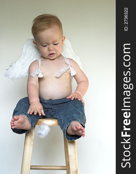 Image of an adorable toddler wearing angel wings and jeans. Image of an adorable toddler wearing angel wings and jeans