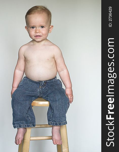 Image of a cute, happy toddler sitting on a stool. Image of a cute, happy toddler sitting on a stool