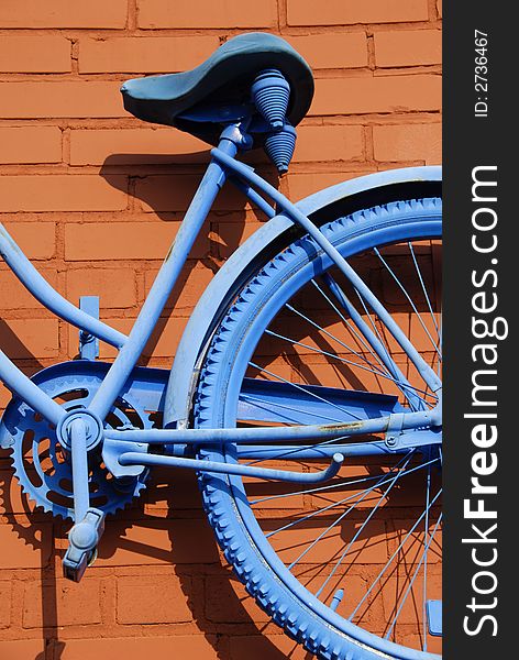 Antique bicycle painted blue and mounted to a rust colored brick wall. Antique bicycle painted blue and mounted to a rust colored brick wall